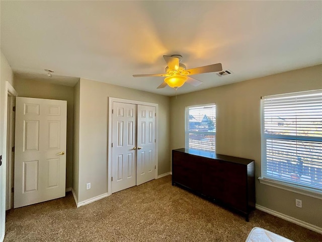 carpeted bedroom featuring ceiling fan and a closet