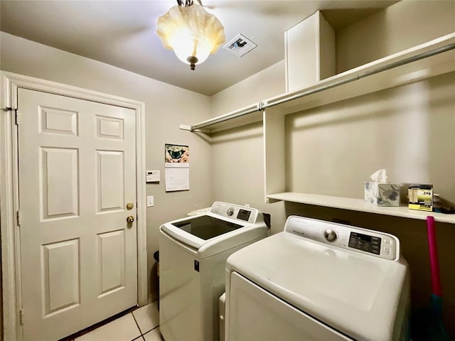 laundry room featuring light tile patterned floors, washer and clothes dryer, and a notable chandelier