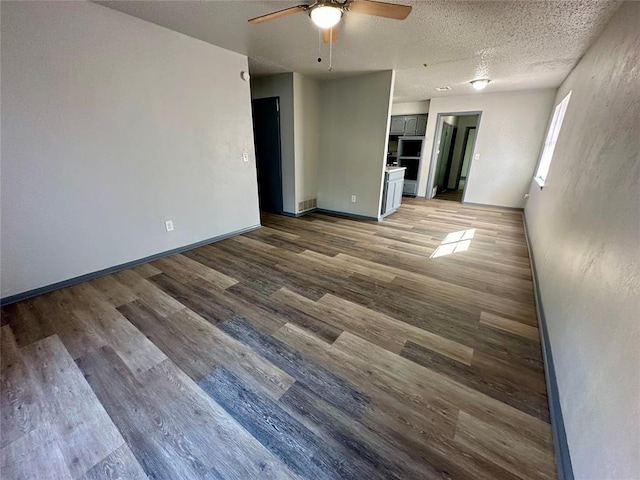 empty room with ceiling fan, a textured ceiling, and wood-type flooring