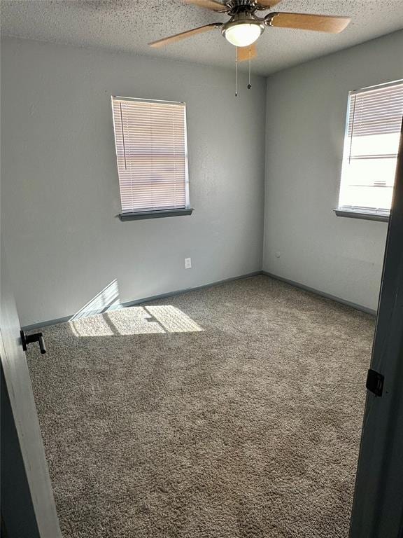 carpeted spare room featuring ceiling fan and a textured ceiling