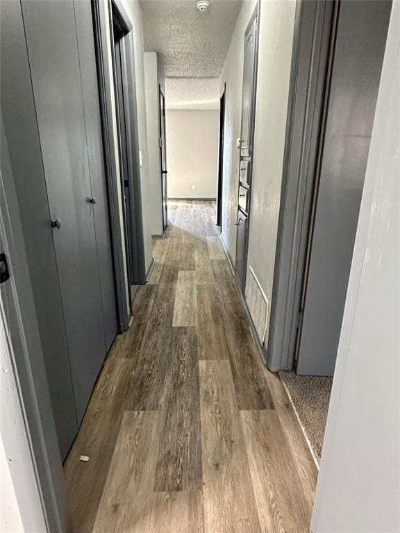 hall featuring a textured ceiling and dark hardwood / wood-style floors