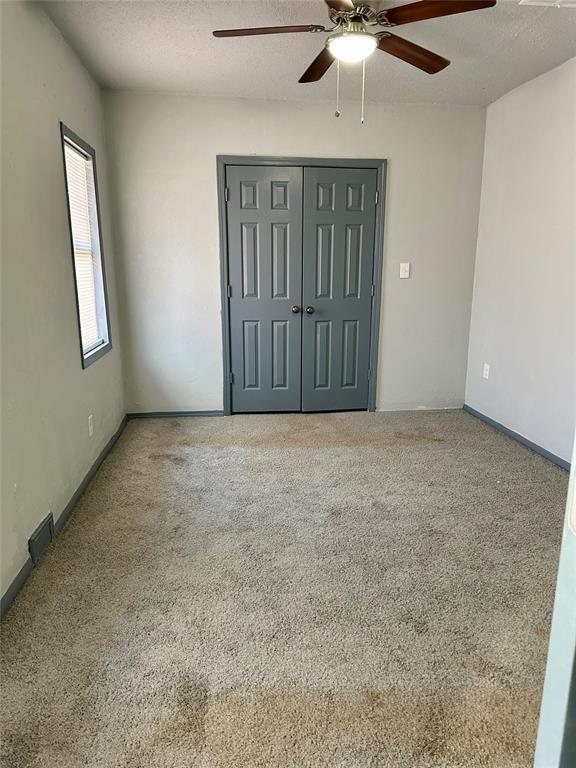 empty room with a textured ceiling and ceiling fan