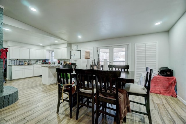 dining room with vaulted ceiling, a healthy amount of sunlight, and light hardwood / wood-style floors