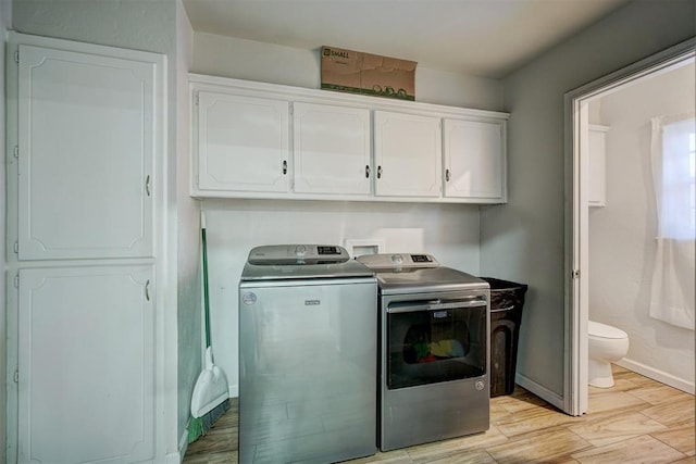 clothes washing area with cabinets, light hardwood / wood-style floors, and washer and clothes dryer