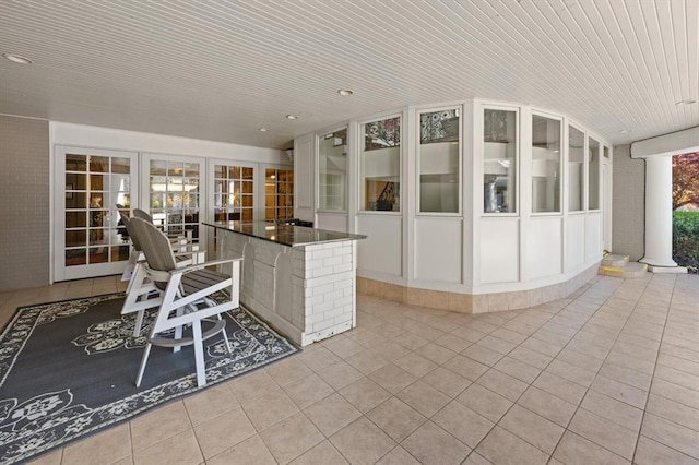 kitchen with wooden ceiling, light tile patterned flooring, and a breakfast bar area