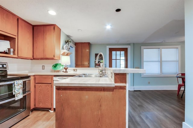 kitchen with sink, light hardwood / wood-style flooring, white dishwasher, double oven range, and a kitchen island with sink