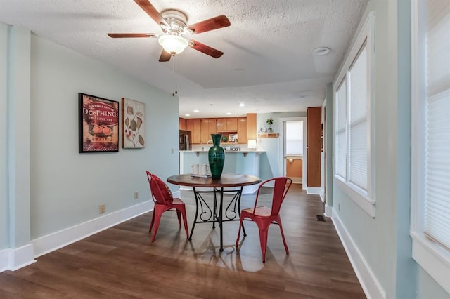 dining space featuring ceiling fan, dark wood-type flooring, and a textured ceiling