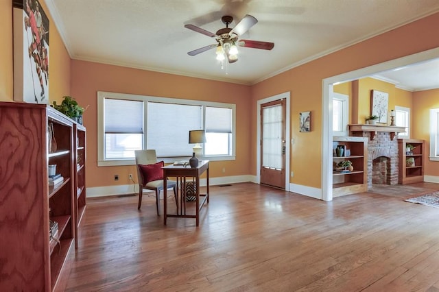 dining room with crown molding, hardwood / wood-style floors, ceiling fan, and a brick fireplace