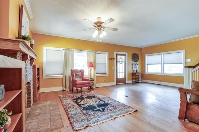 living area featuring light hardwood / wood-style floors, a brick fireplace, ceiling fan, and ornamental molding