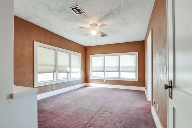 unfurnished room with a textured ceiling, dark carpet, and ceiling fan