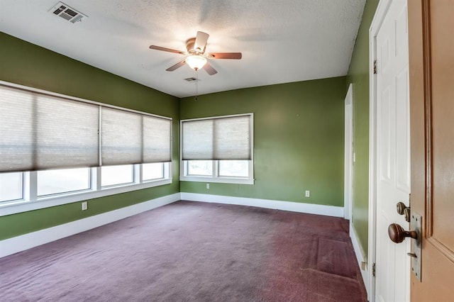 empty room with ceiling fan, dark carpet, and a textured ceiling