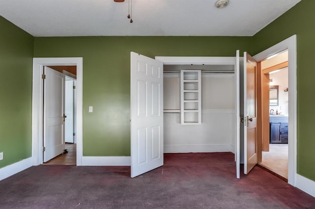 unfurnished bedroom featuring dark colored carpet, a closet, and ceiling fan