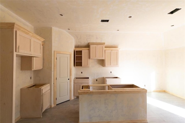 kitchen featuring a kitchen island, baseboards, and light brown cabinets