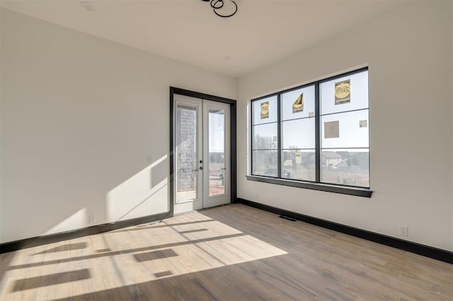 spare room featuring french doors and light wood-type flooring