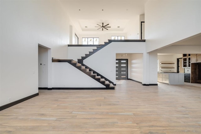 stairs featuring a high ceiling, ceiling fan, and hardwood / wood-style floors