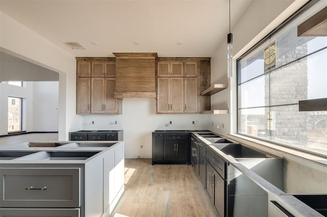 kitchen featuring light hardwood / wood-style floors, wall chimney range hood, and decorative light fixtures