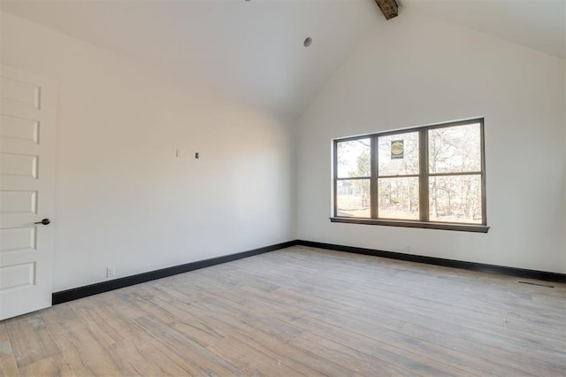 empty room with high vaulted ceiling, beam ceiling, and light hardwood / wood-style floors