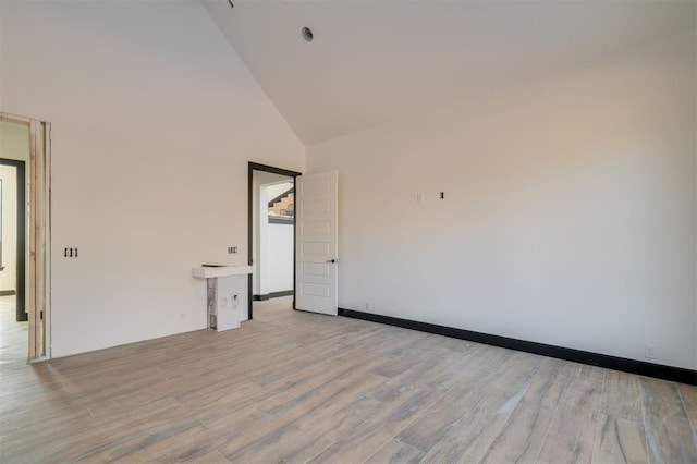 empty room featuring high vaulted ceiling and light hardwood / wood-style flooring