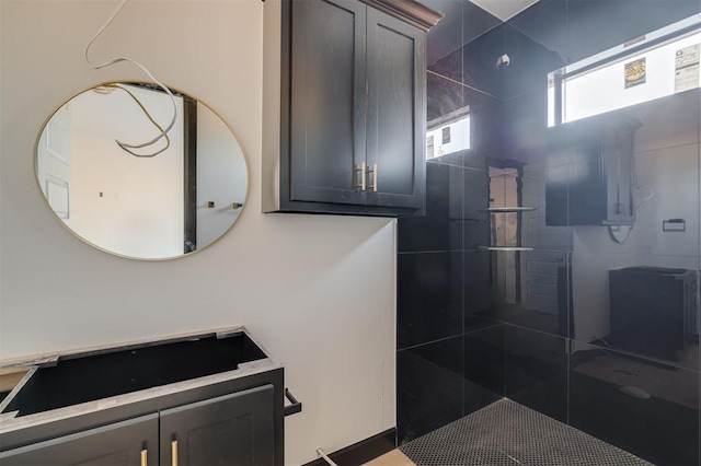 bathroom with a tile shower and vanity