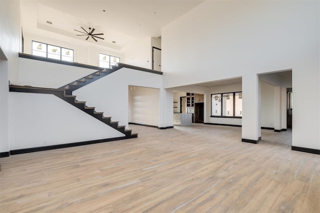 interior space featuring a towering ceiling, ceiling fan, and light hardwood / wood-style flooring