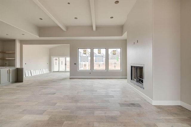 unfurnished living room with built in shelves, light hardwood / wood-style flooring, and beam ceiling