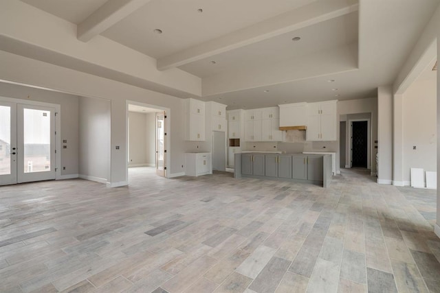 unfurnished living room featuring a high ceiling, french doors, and beamed ceiling