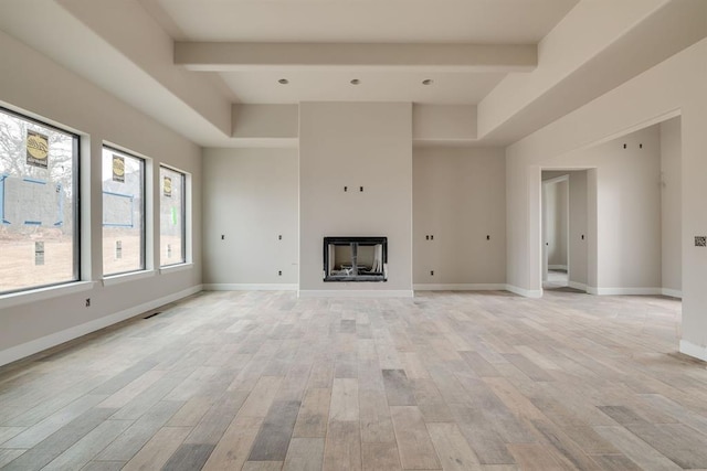 unfurnished living room with beamed ceiling and light hardwood / wood-style floors