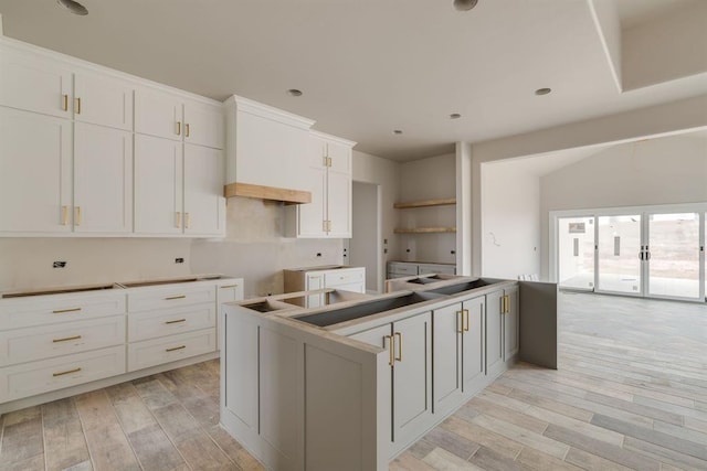 kitchen featuring premium range hood, white cabinetry, a center island, and light hardwood / wood-style floors