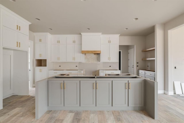 kitchen featuring white cabinetry and an island with sink