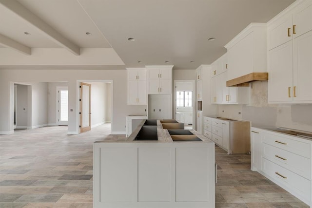 kitchen with a kitchen island, white cabinetry, a healthy amount of sunlight, and beam ceiling