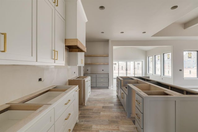 kitchen with custom exhaust hood, white cabinets, and light hardwood / wood-style floors