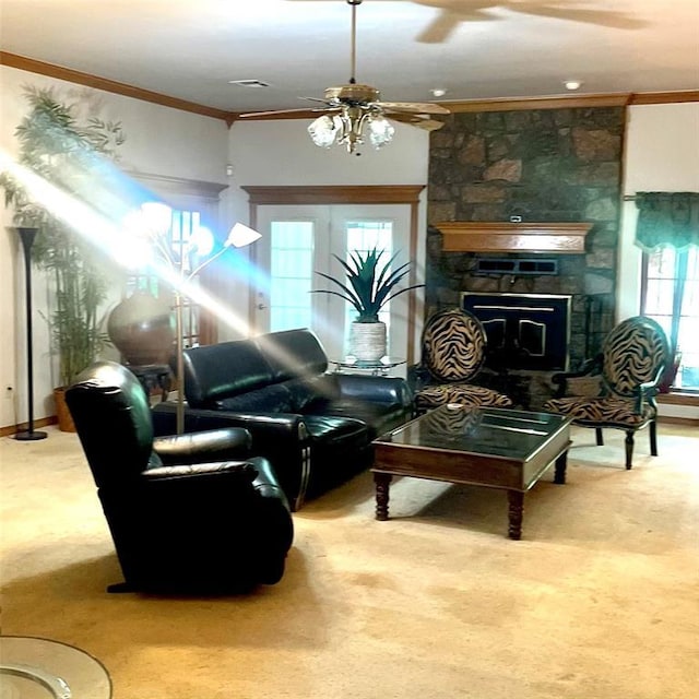carpeted living room featuring crown molding, visible vents, a stone fireplace, and a ceiling fan