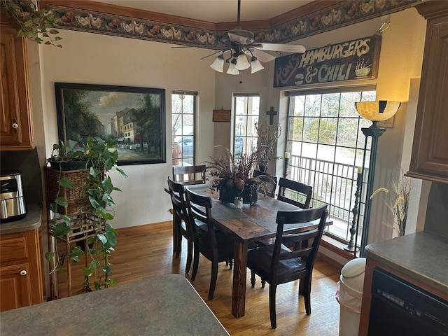dining room featuring baseboards, a ceiling fan, crown molding, and wood finished floors
