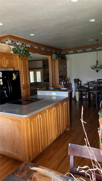 kitchen featuring crown molding, dark countertops, dark wood finished floors, and black appliances