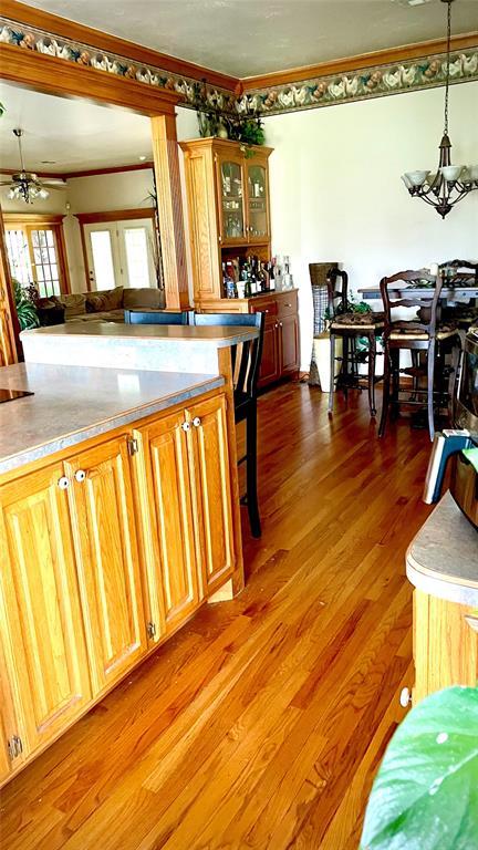kitchen featuring light wood-style flooring, crown molding, decorative light fixtures, and a notable chandelier