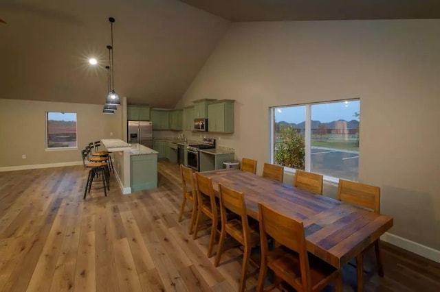 dining area with high vaulted ceiling and light hardwood / wood-style flooring