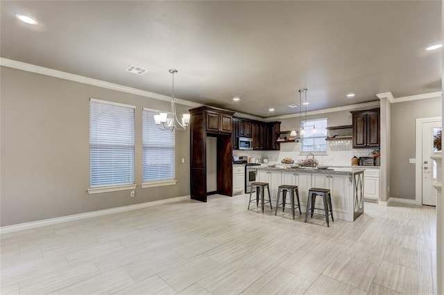 kitchen featuring dark brown cabinetry, a chandelier, a breakfast bar area, a kitchen island, and appliances with stainless steel finishes