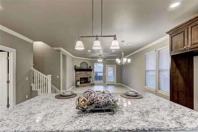 kitchen with light stone countertops, ornamental molding, ceiling fan, decorative light fixtures, and a fireplace