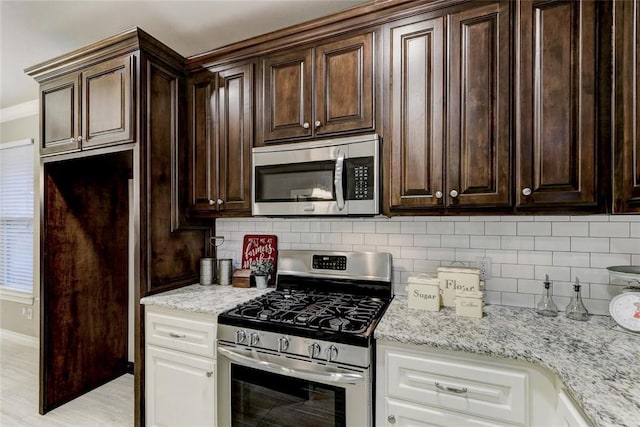 kitchen with tasteful backsplash, light stone counters, and stainless steel appliances