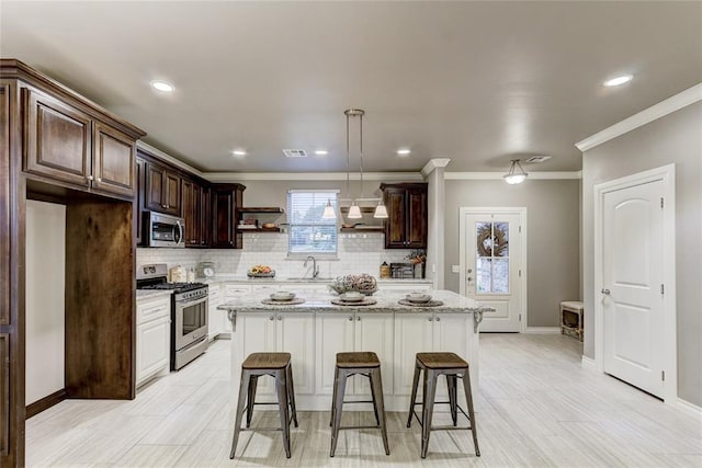 kitchen with appliances with stainless steel finishes, light stone counters, sink, pendant lighting, and a center island