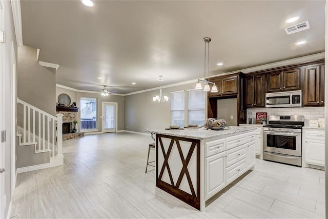 kitchen with dark brown cabinets, ceiling fan with notable chandelier, stainless steel appliances, white cabinets, and hanging light fixtures