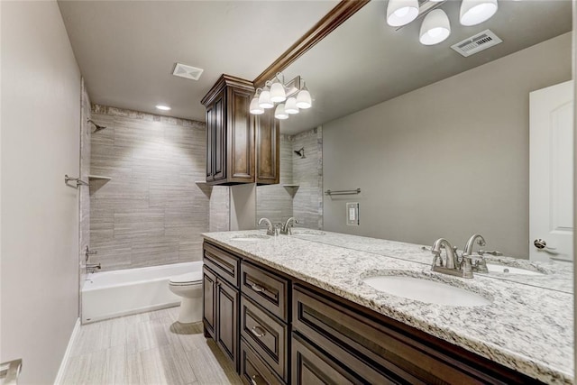 full bathroom with vanity, tiled shower / bath, and toilet