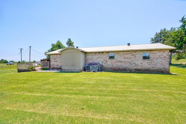 rear view of property with a lawn and central air condition unit