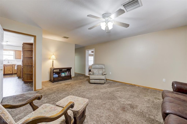 carpeted living room with ceiling fan and sink