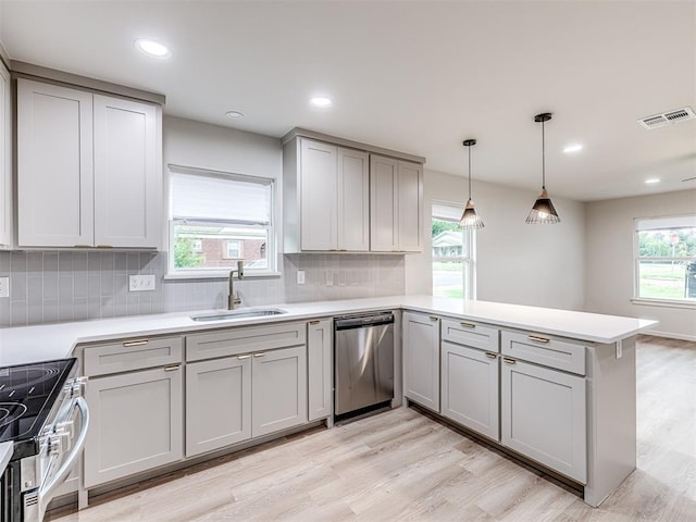 kitchen with appliances with stainless steel finishes, sink, decorative backsplash, hanging light fixtures, and kitchen peninsula