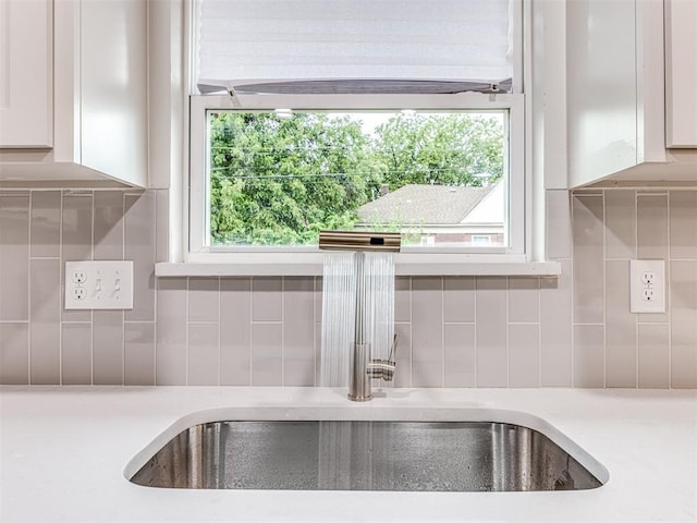 details with white cabinetry, backsplash, and sink