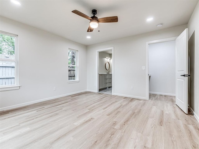 unfurnished bedroom with multiple windows, connected bathroom, ceiling fan, and light hardwood / wood-style floors