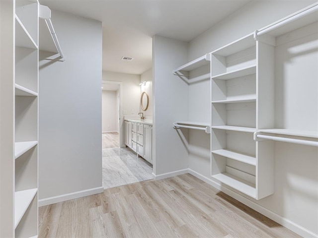 spacious closet with sink and light hardwood / wood-style flooring