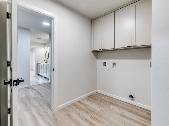 laundry room with cabinets, hookup for a washing machine, and light wood-type flooring