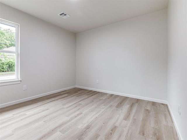 empty room with light hardwood / wood-style flooring and plenty of natural light